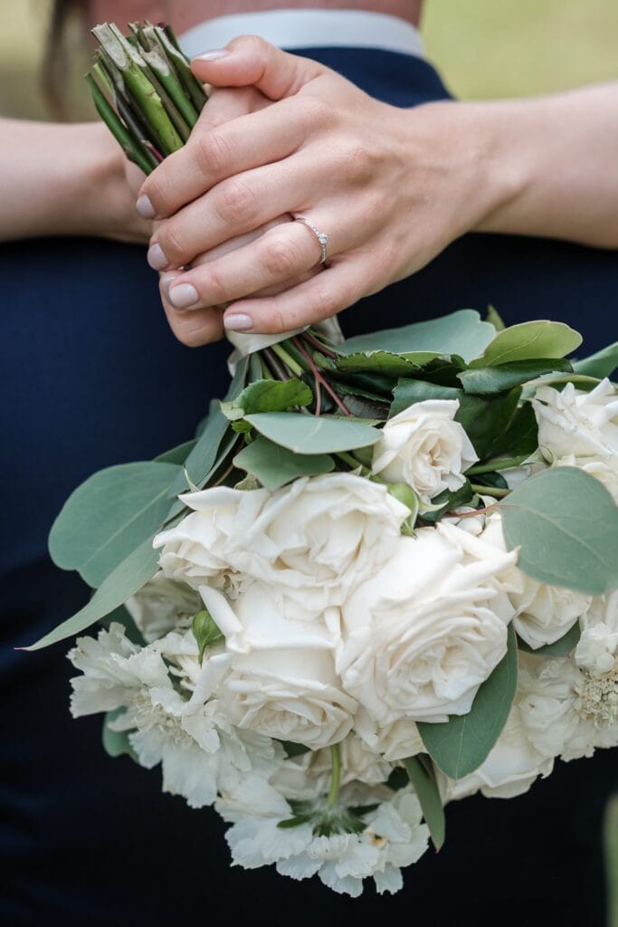 Hochzeitskrone Nahaufnahme einer Person, die einen Strauß weißer Rosen und Grünpflanzen hält, an ihrem Finger glänzt ein Ring – ein Beispiel für „echte Momente“, festgehalten von einem Hochzeitsfotografen in Wien und Niederösterreich.