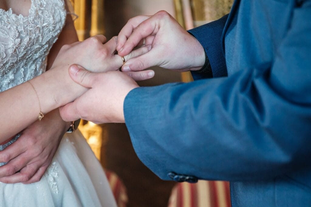 Hochzeitskrone Bei einem bezaubernden Moment in Niederösterreich legt ein Bräutigam der Braut sanft einen Ring an den Finger und fängt so natürliche Emotionen ein, die exquisite Hochzeitsfotografie ausmachen.